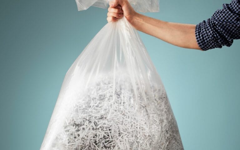 A woman holds a bag of shredded paper at Marshall Shredding