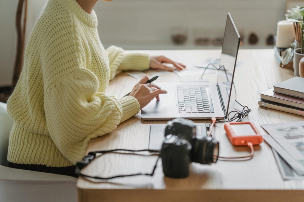 Person working on laptop with camera nearby.