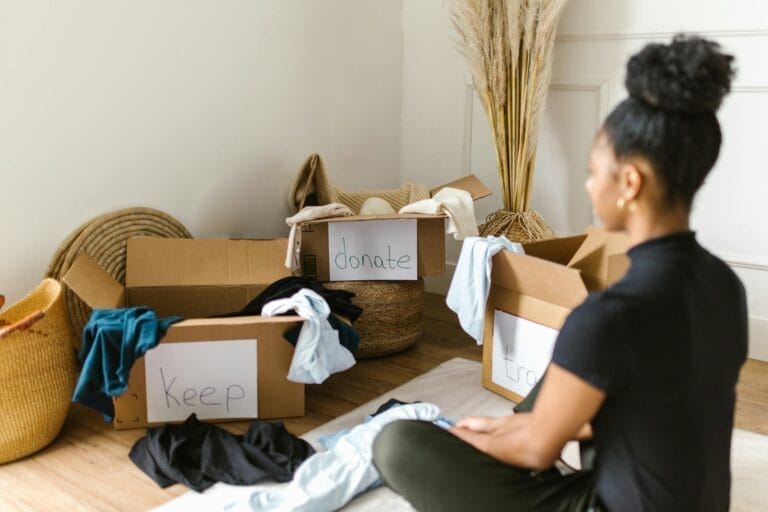 Woman organizing clothes into keep, donate, trash boxes.